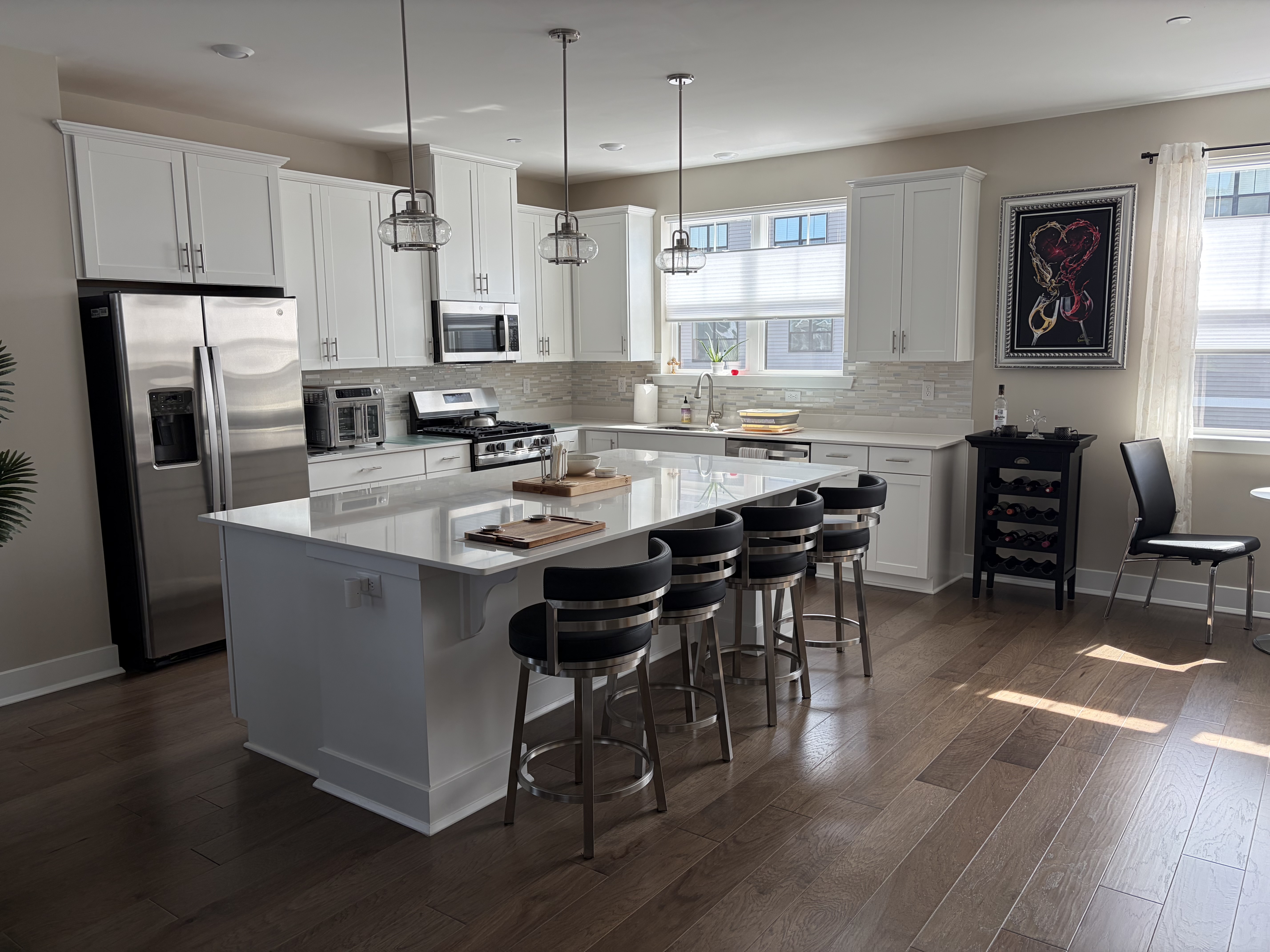 Modern white kitchen remodel with island, stainless appliances and hardwood floors by PJ Restorations